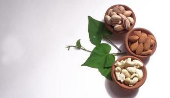 pistagenötter eller pistanötter dekorerade med gröna blad. vanlig bakgrund, ovanifrån. platt låg. foto