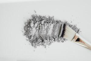 kosmetika mask grå lera på en vit bakgrund. lera och aktiverad träkol mask med borsta. naturlig spa kosmetika. död- hav lera grå bakgrund. topp se. Plats för text. foto