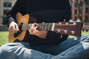 en ung man spelar gitarr i de parkera foto