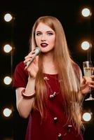 ung smiley vackert långt hår i röd klänning kvinna med mikrofon sjunger sång på scenen i karaoke foto