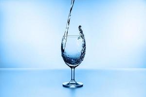 vatten stänk från glas isolerad på blå bakgrund foto
