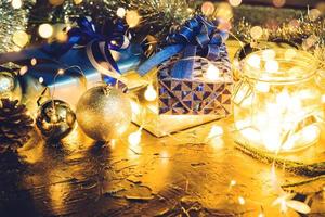 julklapp med blått band och juldekoration bollar på abstrakt bokeh svart bakgrund med kopia utrymme och dekorativa led-lampor. god jul och nytt år. foto