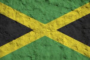 jamaica flagga avbildad i ljus måla färger på gammal lättnad putsning vägg. texturerad baner på grov bakgrund foto