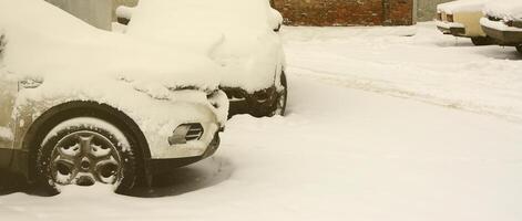 fragment av de bil under en lager av snö efter en tung snöfall. de kropp av de bil är täckt med vit snö foto