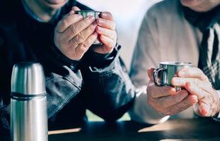 senior par händer som håller koppar med varmt kaffe foto