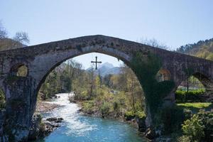 antik romersk bro vid cangas de onis, asturien, med ett kors hängande från det som en symbol för seger foto