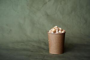 en låda av popcorn på en färgad bakgrund, en hantverk burk, snabb mat i de begrepp av minimalism, mat för de bio foto