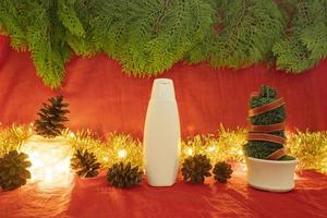 minimalistisk konceptidé som visar produkter. kosmetiska flaskor på jul och nyår bakgrund. rött, ljus, tallblommor foto