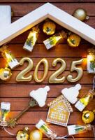 hus nyckel med Nyckelring stuga på festlig brun trä- bakgrund med stjärnor, lampor av girlanger. ny år 2025 gyllene brev under de tak. inköp, konstruktion, flytt, inteckning, försäkring foto