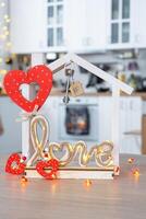 nyckel till mycket liten hus av mysigt Hem med valentine dekor på tabell av kök. gåva för valentines dag, familj kärlek bo. design, projekt, rör på sig till ny hus, inteckning, hyra och inköp verklig egendom foto