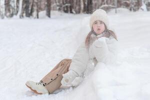 söt liten flicka i vinter- promenader i vinter- snötäckt skog. vinter- aktiviteter, tidsfördriv, promenad foto