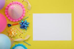 grattis på födelsedagen bakgrund, platt lägga färgglada fest dekoration med reklamblad inbjudan på pastell gul bakgrund foto