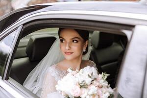 en skön brud, Sammanträde i en bil, utseende ut av de öppen fönster av de bil. en skön brud med en bukett av blommor i henne händer är Sammanträde i en eleganta dyr bil. foto