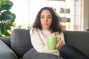latinsk kvinna dricker kaffe på soffan