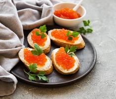 röd kaviar i skål och smörgåsar foto