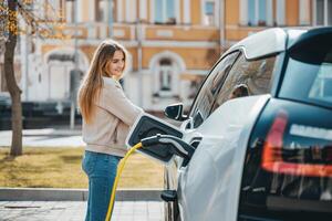 ai genererad kvinna använder sig av ev bil laddning station för avgift ev batteri. plugg för fordon med elektrisk motor. rena energi. laddning punkt på bil parkering massa. framtida transport teknologi modern bil. foto