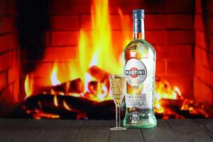 Kiev, ukraina - Maj 4, 2022 vermouth Martini original- alkohol flaska på trä- tabell med öppen spis foto