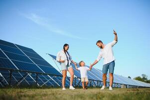 Lycklig ung familj nära sol- paneler. sol- energi. foto