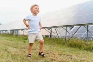 en liten pojke är har roligt nära de sol- paneler. de begrepp av sol- energi. foto