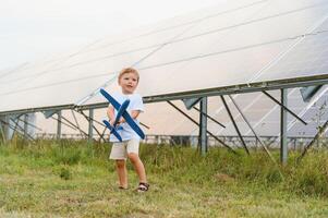 liten Lycklig pojke spelar med leksak flygplan nära sol- paneler. foto