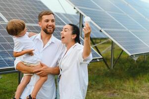 de begrepp av förnybar energi. ung Lycklig familj nära sol- paneler foto