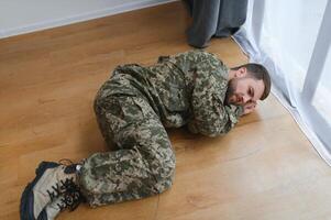 militär man liggande deprimerad på de golv på Hem. ptsd foto