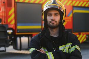 brandman porträtt på plikt. brandman med hjälm nära brand motor foto