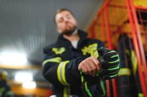 en brandman sätter på en brand enhetlig på de brand avdelning foto