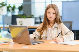 först dag på skola. söt och Lycklig liten flicka barn använder sig av bärbar dator dator, studerar genom uppkopplad e-learning systemet foto