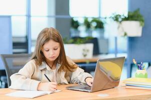 först dag på skola. söt och Lycklig liten flicka barn använder sig av bärbar dator dator, studerar genom uppkopplad e-learning systemet foto