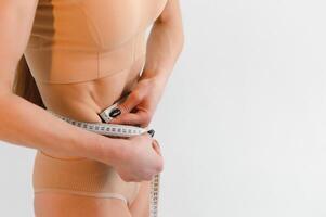 kvinna mätning henne smal kropp isolerat på vit bakgrund. foto
