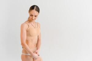 kvinna mätning henne smal kropp isolerat på vit bakgrund foto