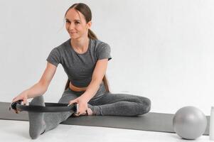 passa ung brunett pilates instruktör som visar annorlunda övningar på en vit bakgrund en matta. foto