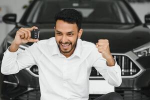 närbild porträtt Lycklig, leende, ung man, köpare som visar nycklar av hans ny bil foto