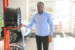 ett afrikansk man köper bil fälgar i ett bil delar Lagra foto