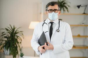 porträtt av sjukvård arbetstagare. bild av senior manlig läkare bär labb täcka och stående på privat klinik foto