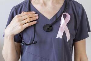 skott av de kvinna läkare mot de vit vägg med rosa band, som en symbol av en bröst cancer medvetenhet. begrepp foto