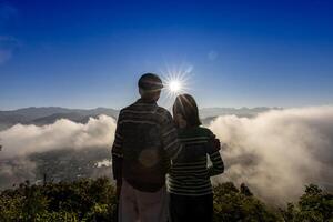 tillbaka se av senior par tittar på soluppgång tillsammans med panorama- dimmig berg se efter vandring till de topp för kärlek, äktenskap och friska lång sista relation bindning begrepp foto