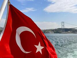 turkiska flagga fladdrande i de vind med istanbul och de gyllene horn bro i de bakgrund, Kalkon foto