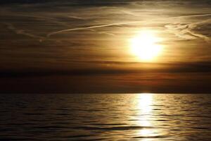gyllene Sol strålar reflexion på de hav på solnedgång foto
