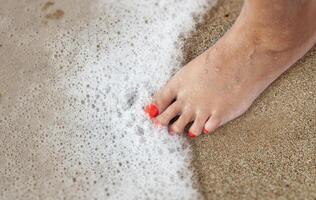 kvinnors fötter med en pedikyr i de sand på de strand foto