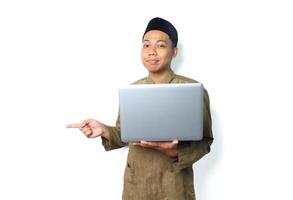 lugna fredlig asiatisk muslim man innehav bärbar dator pekande till bredvid isolerat på vit bakgrund foto