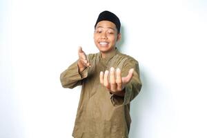 Lycklig asiatisk muslim man bär koko kläder presenter på kamera med öppen palmer isolerat på vit bakgrund foto