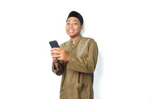 Lycklig asiatisk muslim man surfing i cyberrymden använder sig av mobil telefon isolerat på vit bakgrund foto