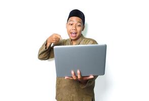 överraskad asiatisk muslim man pekande till bärbar dator isolerat på vit bakgrund foto