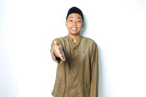 Lycklig asiatisk muslim man bär koko kläder erbjudande vänlig handslag på kamera isolerat på vit bakgrund foto