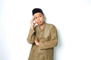 omtänksam asiatisk muslim man tänkande allvarligt med rörande hans huvud bär koko kläder isolerat på vit bakgrund foto