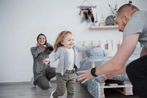 lycklig familj har roligt hemma. mamma, pappa och lilla dotter med plysch leksak njuter av att vara tillsammans foto