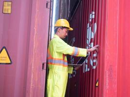 manlig man personal bistånd arbetskraft gul Hardhat säkerhet hjälm pekande finger kolla upp upp behållare frakt metall stål anteckningsbok uppsättning upp dator arbete jobb importera exportera behållare lager terminal företag foto