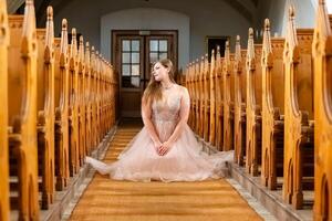 ung kvinna i en rosa klänning knäböj i en kyrka foto